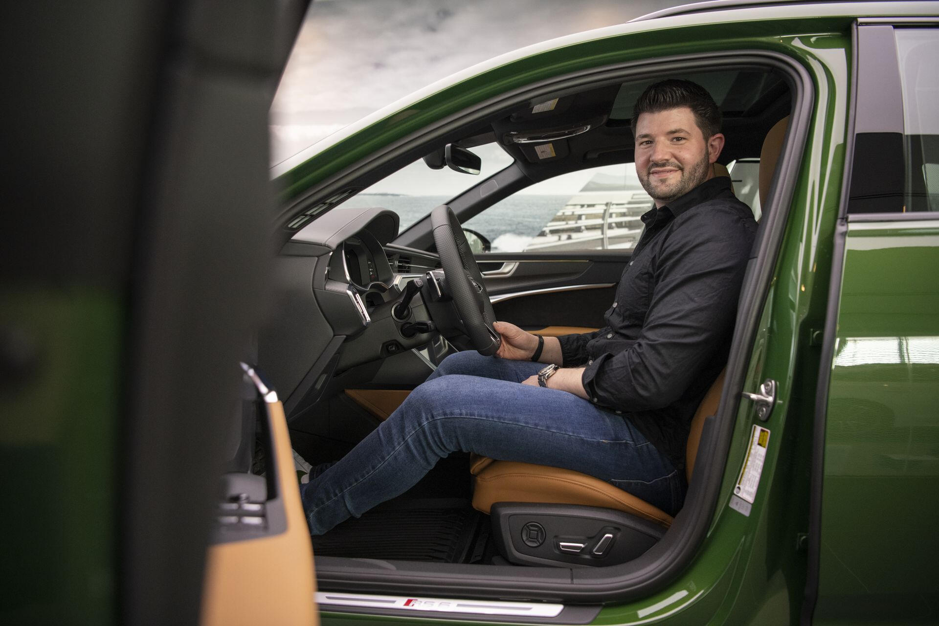 Brian Karschti sitting in the driver's seat of his green Audi RS6