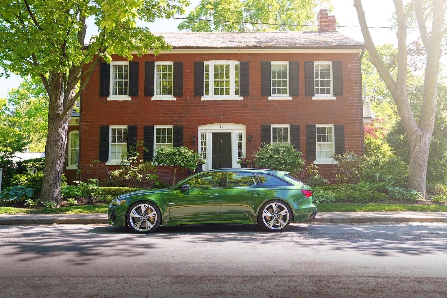 Green Audi RS6 parked in front of a red brick heritage home in Ancaster